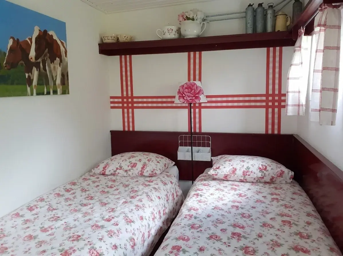 De slaapkamer met twee eenpersoonsbedden en rood-wit beddengoed